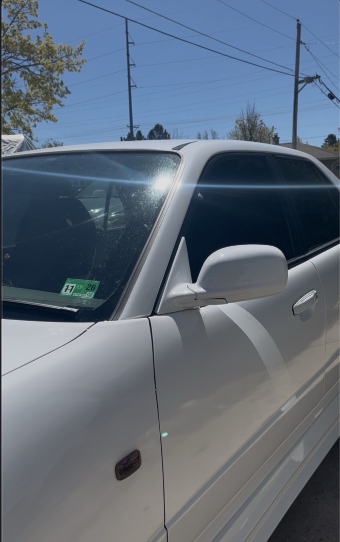 White Nissan Skyline with dark window tint in sunlight
